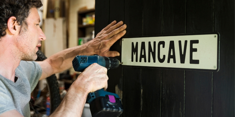 man installing mancave sign on door